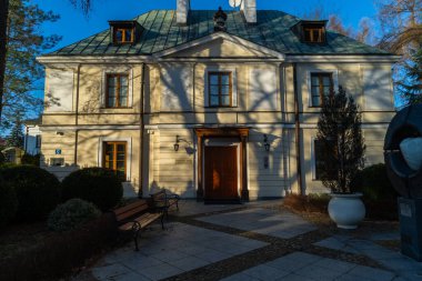 Varşova, Polonya 'daki Wilanowski Sarayı yakınlarındaki St. Anne Kilisesi' nde eski bir bina. Mavi gökyüzü güneşli ve ağaçların gölgesi altında.