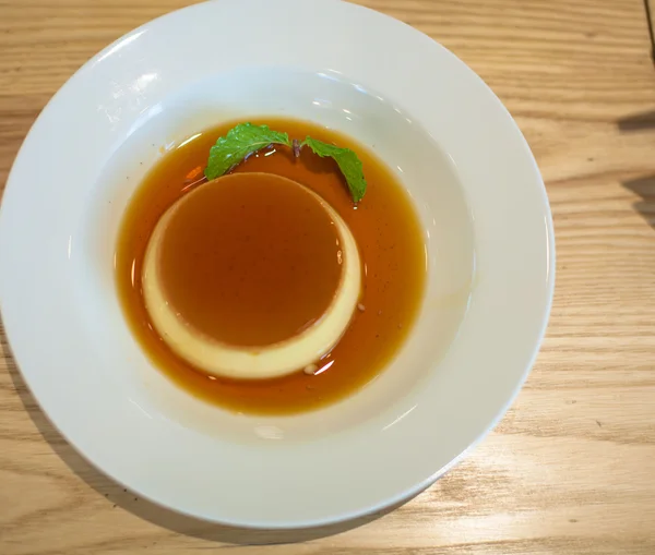 Delicious pudding with caramel and mint leaves. On a white backg — Stock Photo, Image