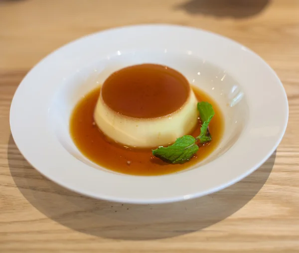 Delicious pudding with caramel and mint leaves. On a white backg — Stock Photo, Image