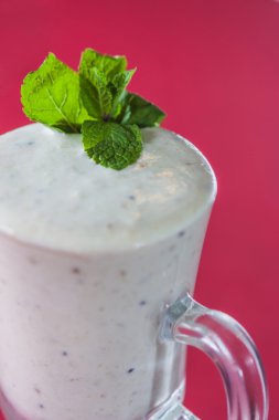 çilek yaprağı pembe bir arka plan üzerine bir bardak muzlu süt