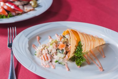 bir waffle koni sos ve yuvarlak beyaz tabakta yeşillik salatası