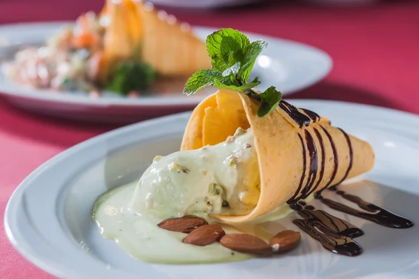 Вафельний конус з рідким шоколадом, мигдалем і листям полуниці — стокове фото