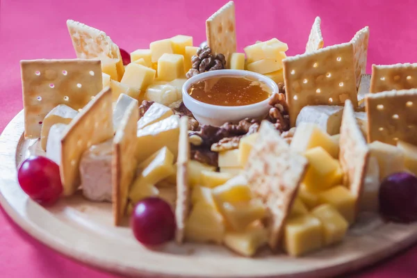 Rebanadas de queso con uvas, galletas saladas, nuez y miel en un cr —  Fotos de Stock