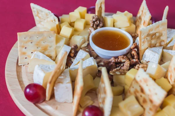 Rebanadas de queso con uvas, galletas saladas, nuez y miel en un cr —  Fotos de Stock