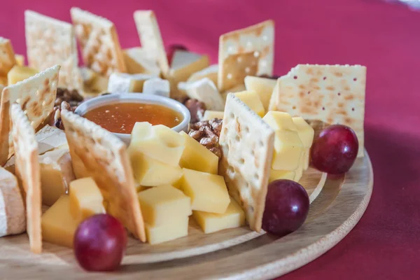 Diferentes variedades de queso con uvas, galletas saladas, frutos secos y ho — Foto de Stock