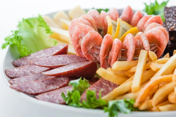 Assorted snacks: cheese, salami, shrimp, french fries — Stock Photo, Image