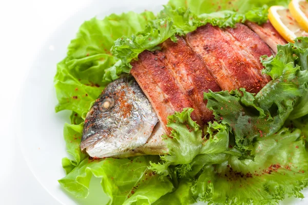 Grilled fish and bacon with lettuce and lemon. on a white backgr — Stock Photo, Image
