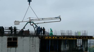 NOVOSIBIRSK, RUSSIA - 14 Temmuz 2020: İnşaat işçileri yüksek binalarda beton örümcek hortumu ya da pompa ile ıslak beton döküyorlar. Yağmurda çalışmak