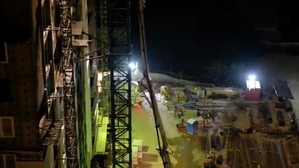 Trabajadores de la construcción vertiendo hormigón húmedo utilizando manguera de araña de hormigón o trabajo de bomba en el sitio de gran altura en la noche — Vídeo de stock