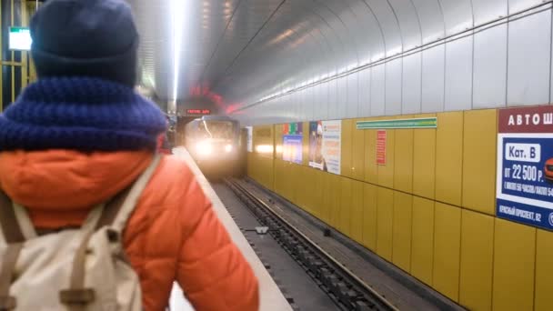 RUSSIA, NOVOSIBIRSK - 03 mrt 2020: vrouw op metrostation wachtend op trein op perron. Metro arriveert — Stockvideo