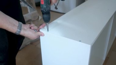 Yaşlı adam mobilya sondajı yapıyor. Evdeki yenileme işlerinde sondaj yapıyor.