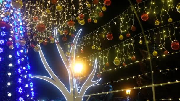 Valaistus Joulukoristeet, seppeleitä ja valoja yöllä kaupungin aukiolla — kuvapankkivideo