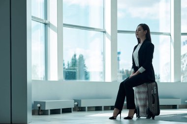 Havaalanındaki genç Asyalı iş kadını, el çantasıyla kalkışı bekliyor..