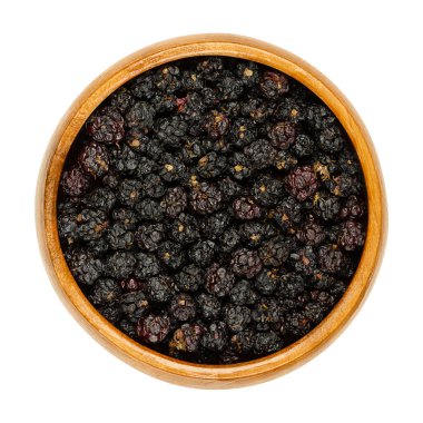 Tahta bir kasede kurumuş Avrupa böğürtlenleri. Havada kurutulmuş yabani çalılar, Rubus fruticosus, tatlı bir meyve, çay katkı maddesi olarak kullanılır. Yukarıdan yakın plan, beyaz arkaplanda izole edilmiş, makro yiyecek fotoğrafı.