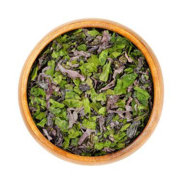 Tahta bir kasede yosun taneleri. Dul (Palmaria palmata), deniz marulu (Ulva lactuca) ve nori karışımı. Kurutulmuş deniz yosunu, doğal iyot açısından zengin, çorbalar, salatalar ve diğer yemekler için baharat olarak kullanılır..