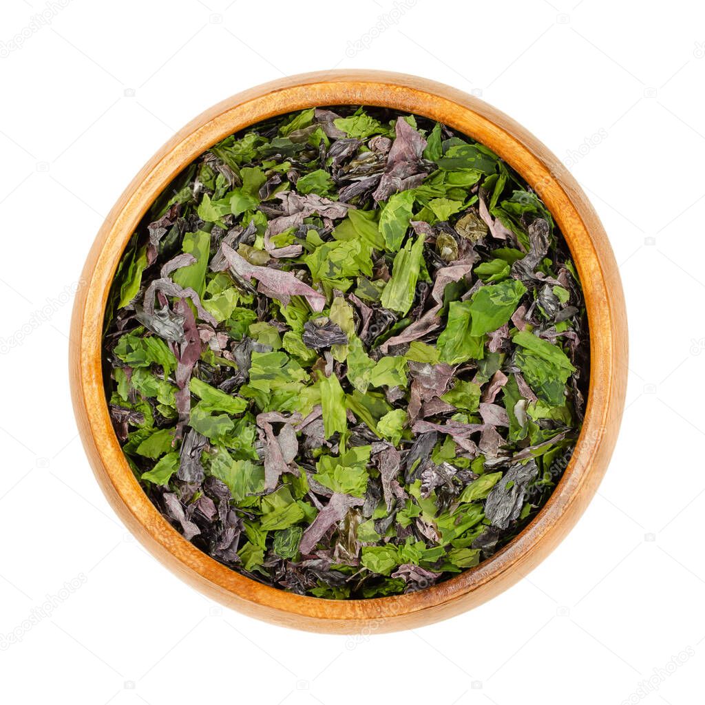 Seaweed flakes in a wooden bowl. Mix of dulse (Palmaria palmata), sea lettuce (Ulva lactuca) and nori. Dried marine algae, rich in natural iodine, used as seasoning for soups, salads and other dishes.