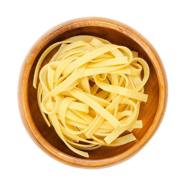 未煮熟的 干的意大利面 在一个木制碗里 传统类型的鸡蛋面食 来自意大利的埃米莉亚 罗马纳和马什地区 长而平的缎带 宽约6毫米 扭曲成一个小窝 — 图库照片