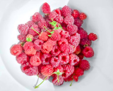 Yukarıdan, beyaz bir tabakta taze ahududu. Taze toplanmış, olgun, kırmızı ve tatlı Rubus Idaeus meyveleri, Avrupa ahududu ekimi. Organik ve vejetaryen meyveler. Yakın çekim, yemek fotoğrafı..