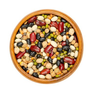 Tahta bir kasede, yukarıdan gelen kurutulmuş darbeler. Kırmızı böbrek, siyah ve beyaz fasulye, fasulye, kahverengi, yeşil ve kırmızı mercimek ve nohut karışımı. İzole edilmiş, beyaz arka planda, yemek fotoğrafı..