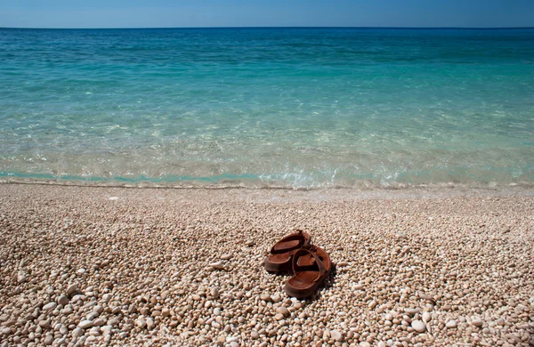 Brown flip flops at Porto Katsiki beach on Lefkada island Greece — Stock Photo, Image