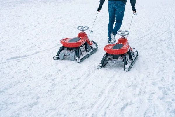 冬季男子拉着两只滑雪板和方向盘在雪地上滑行 — 图库照片