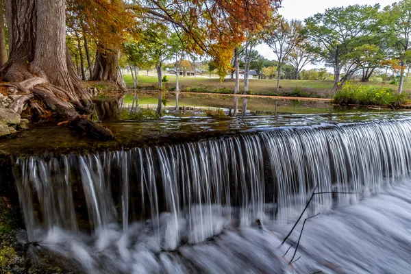 Schöner fließender Wasserfall mit großen Zypressen und riesigen knorrigen Wurzeln im texanischen Hügelland. — Stockfoto