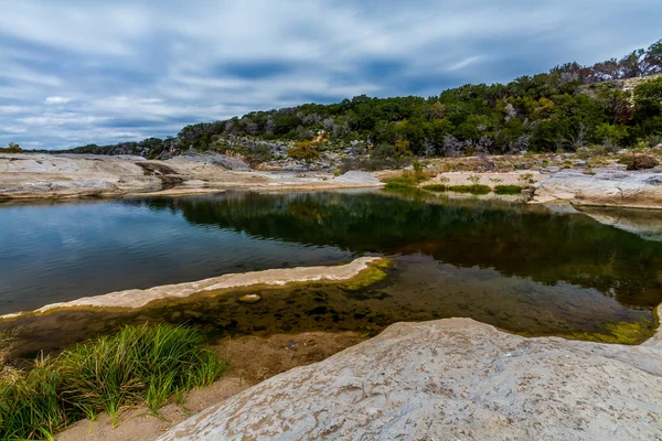 Vackra klippformationer ristade smidig av kristallklart blågrönt vatten i floden pedernales med slående höstfärger. — Stockfoto