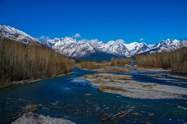 Masmavi gökyüzü, buzul zümrüt nehir ve küçük bir Alaska yerleşim ile şapkalı kar Dağları — Stok fotoğraf