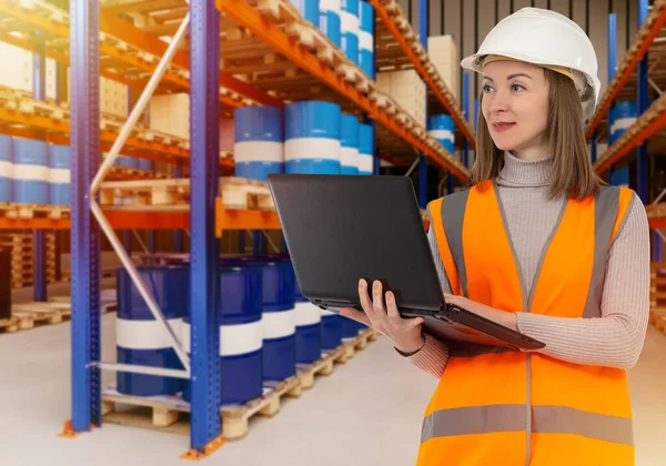 Warehouse worker near barrels. Warehouse for chemical products. Woman warehouse manager. Logistics center employee. Barrels chemistry or oil behind girl. Work in chemical industry. Selective focus
