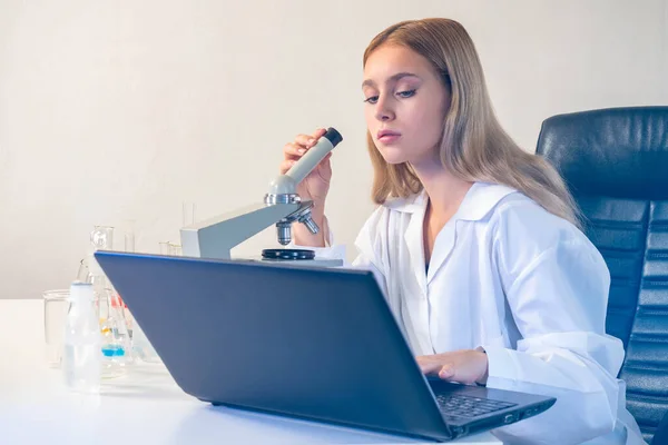 Scientific research concept. Woman scientist in laboratory. girl is engaged in scientific research. Laboratory assistant with laptop. Mikraskom on scientist\'s table. Scientific work.