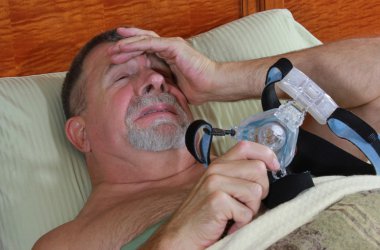 Senior Adult Man frustrated with his CPAP in Bed clipart