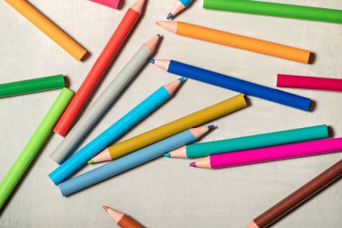 Okul kalemleri gri arka plana saçılmış.