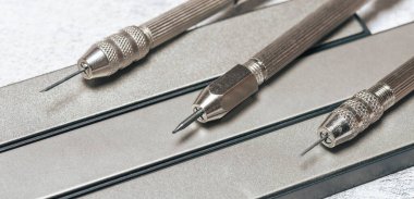 Keskinleştirmek için elmas bileme taşlarının üzerine keskin kazıyıcılar. Bozuk paraların mekanik temizliği ve arkeolojik eşyalar