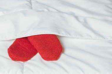 Beyaz battaniyenin altında kırmızı eldivenler. Ev konforunun sıcaklığı