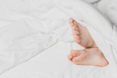 Childs 'ın bacakları beyaz çarşaflarla kaplı. Ev konforunun sıcaklığı