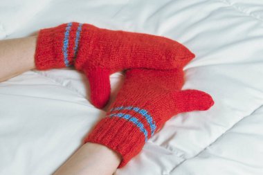 Beyaz battaniyede kırmızı eldivenli kadın elleri. Ev konforunun sıcaklığı