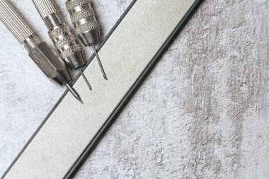 Keskinleştirmek için elmas bileme taşlarının üzerine keskin kazıyıcılar. Bozuk paraların mekanik temizliği ve arkeolojik eşyalar