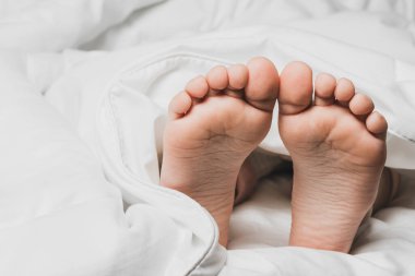 Childs 'ın bacakları beyaz çarşaflarla kaplı. Ev konforunun sıcaklığı