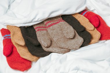 Beyaz battaniyeye örülmüş eldivenler. Ev konforunun sıcaklığı
