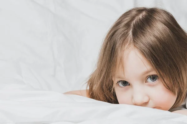 美しい少女は白いリネンのベッドの上に横たわっている 家庭の快適さの暖かさ ロイヤリティフリーのストック写真