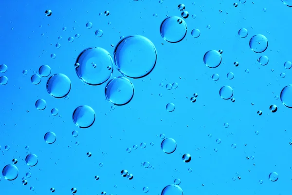 Vatten droppar på blå Stockfoto