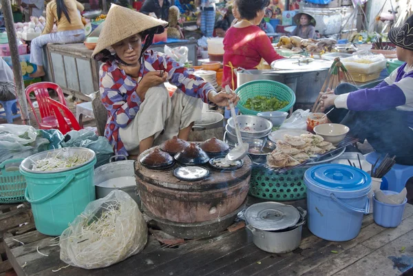 Vietnamesin mit kegelförmigem Hut kocht traditionelle Pfannkuchen. — Stockfoto
