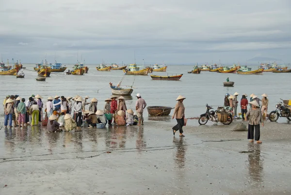 Femmes vietnamiennes dans des chapeaux coniques traditionnels "non" attendre bateaux de pêche sur la plage à Mui Ne, Vietnam . — Photo