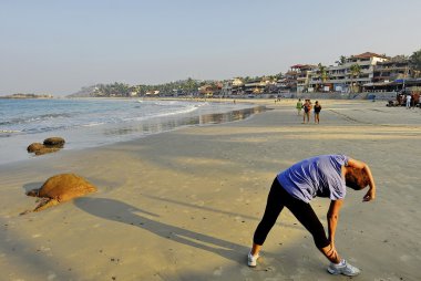 Batı turist Kerala, Hindistan kovalam plajda erken sabah egzersizleri yapar.