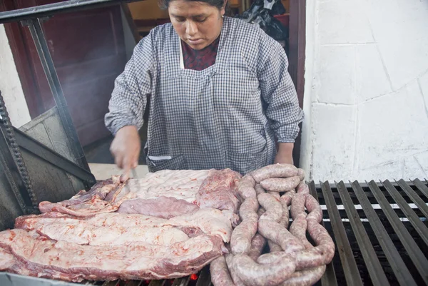 Bolivian woman cooks traditional grilled pork on a street in La Paz, Bolivia.