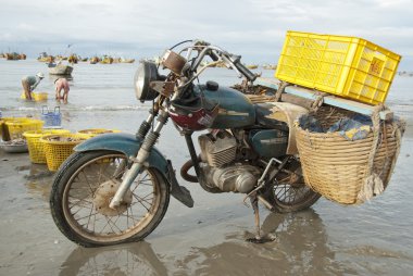 Old motorcycle made in Soviet Union waits loading on the beach in Mui Ne, Vietnam. clipart