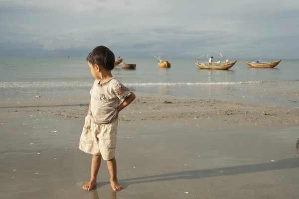 越南男孩等待返回他的父母亲从渔船在越南美奈的海滩上. — 图库照片