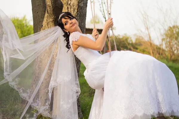 Portrait of a beautiful bride in white wedding dress sitting on — Stock Photo, Image