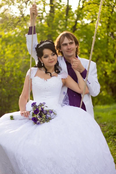 Bride and groom swinging on a swing — Stock Photo, Image