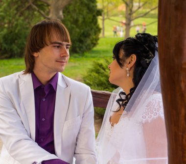 iki aşk gelin ve damat tahta bankta oturmuş poz içinde